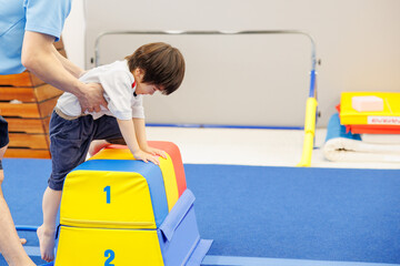 職員に支えられて跳び箱に登る子ども